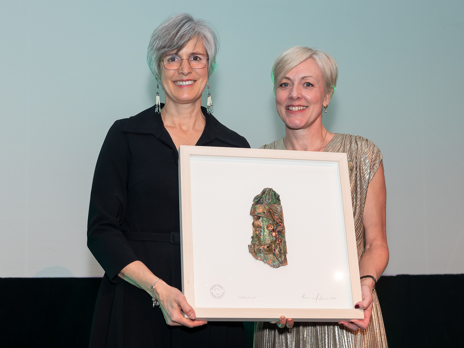 Mme Sophie d'Amours, ambassadrice d'honneur 2025, en compagnie de Mme Caroline Lepage, PDG du Centre des congrès de Québec, tenant dans leurs mains un cadre honorifique.